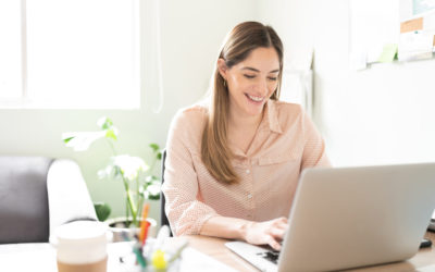 Portrait of a good looking Caucasian businesswoman smiling while using a laptop computer in an office