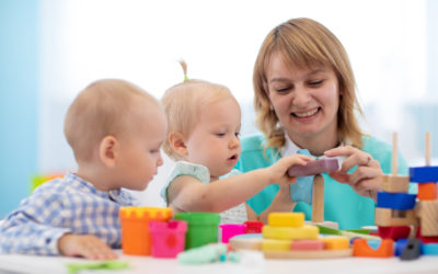 Little caucasian baby playing with Montessori toy in creche or pre-school